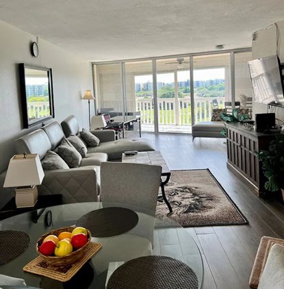 Living room with sofas facing the glass sliding doors that open onto the golf-course balcony